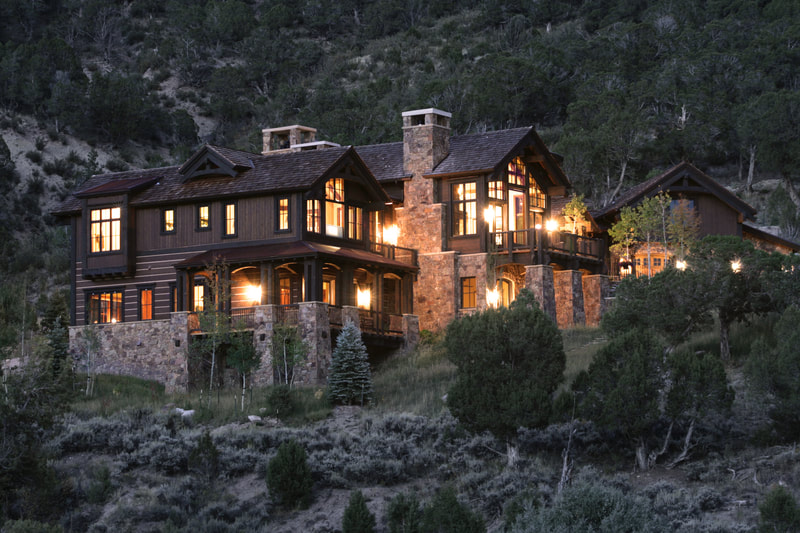 Mountain home close to a steep, forested slope.